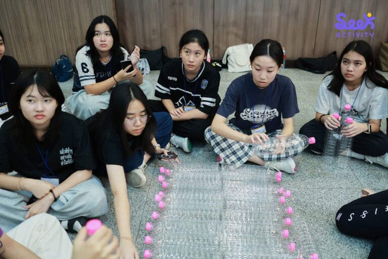 นักเรียนกำลังนั่งล้อมวงช่วยกันสร้างสิ่งประดิษฐ์และต่อขวดพลาสติก ในกิจกรรมฐานวิทยาศาสตร์